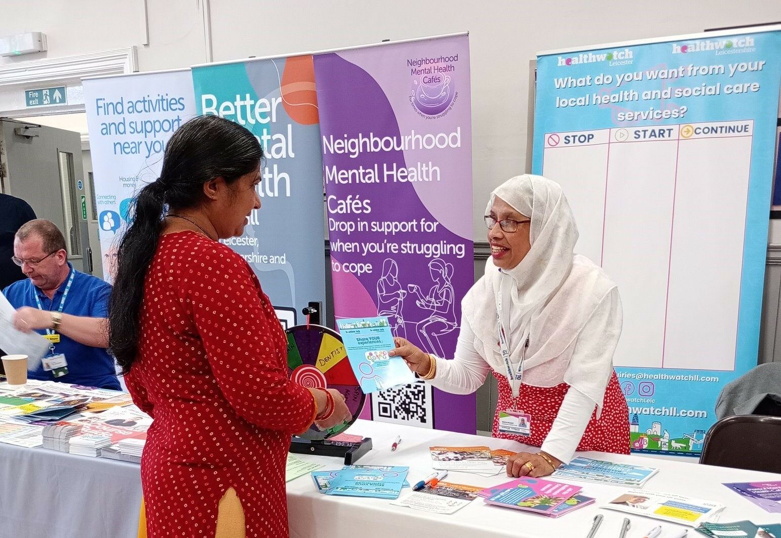 Healthwatch outreach officer giving a leaflet to a female member of the public at an event in Belgrave, Leicester.